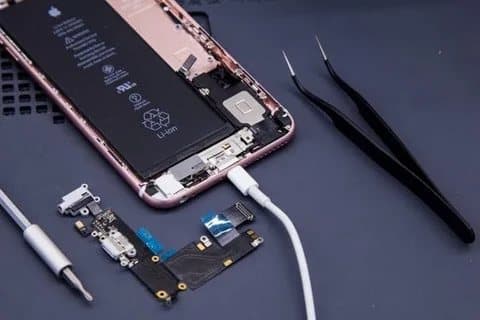 iPhone charging port assembly removed beside the opened phone