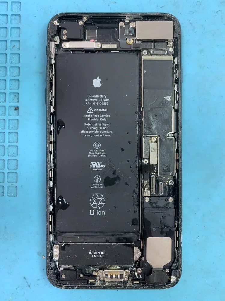 Opened iPhone with liquid droplets on the battery